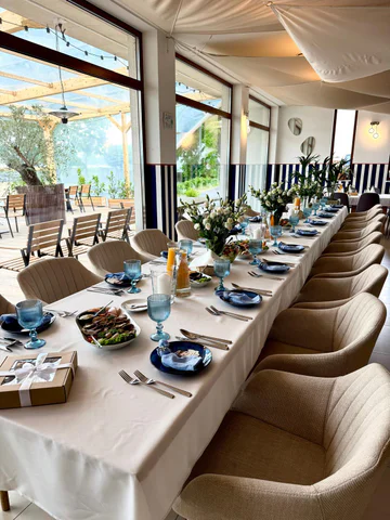 A long table laid for a celebration in the restaurant, with flowers and blue glasses