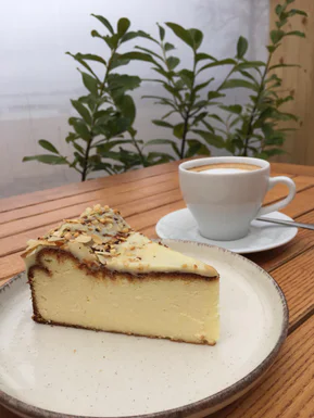 A slice of cheesecake and a cup of coffee on a wooden table