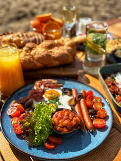 Breakfast: a fried egg, sausages, beans, cherry tomatoes and lettuce on a blue plate