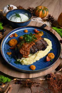Meat in sauce on mashed potato, served on a blue plate