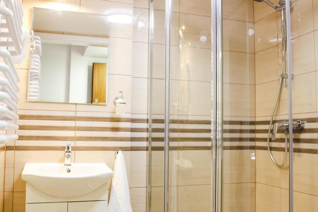Bathroom with a shower cubicle, washbasin, mirror and towel radiator