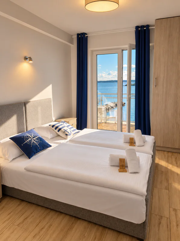 Room with a double bed, a compass-rose cushion and open doors to a balcony over the lake