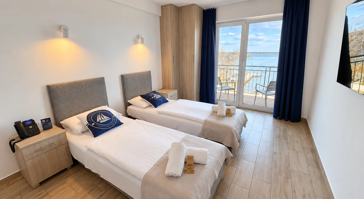 Room with two single beds and doors to a balcony looking out over the lake
