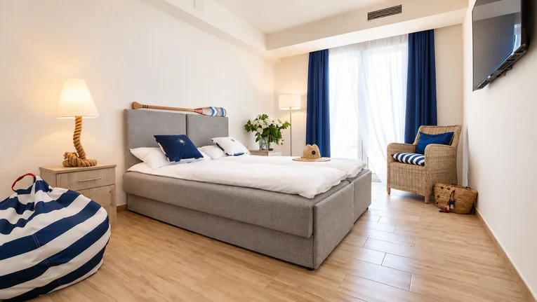 Room with a double bed, armchair and TV, decorated in navy and white